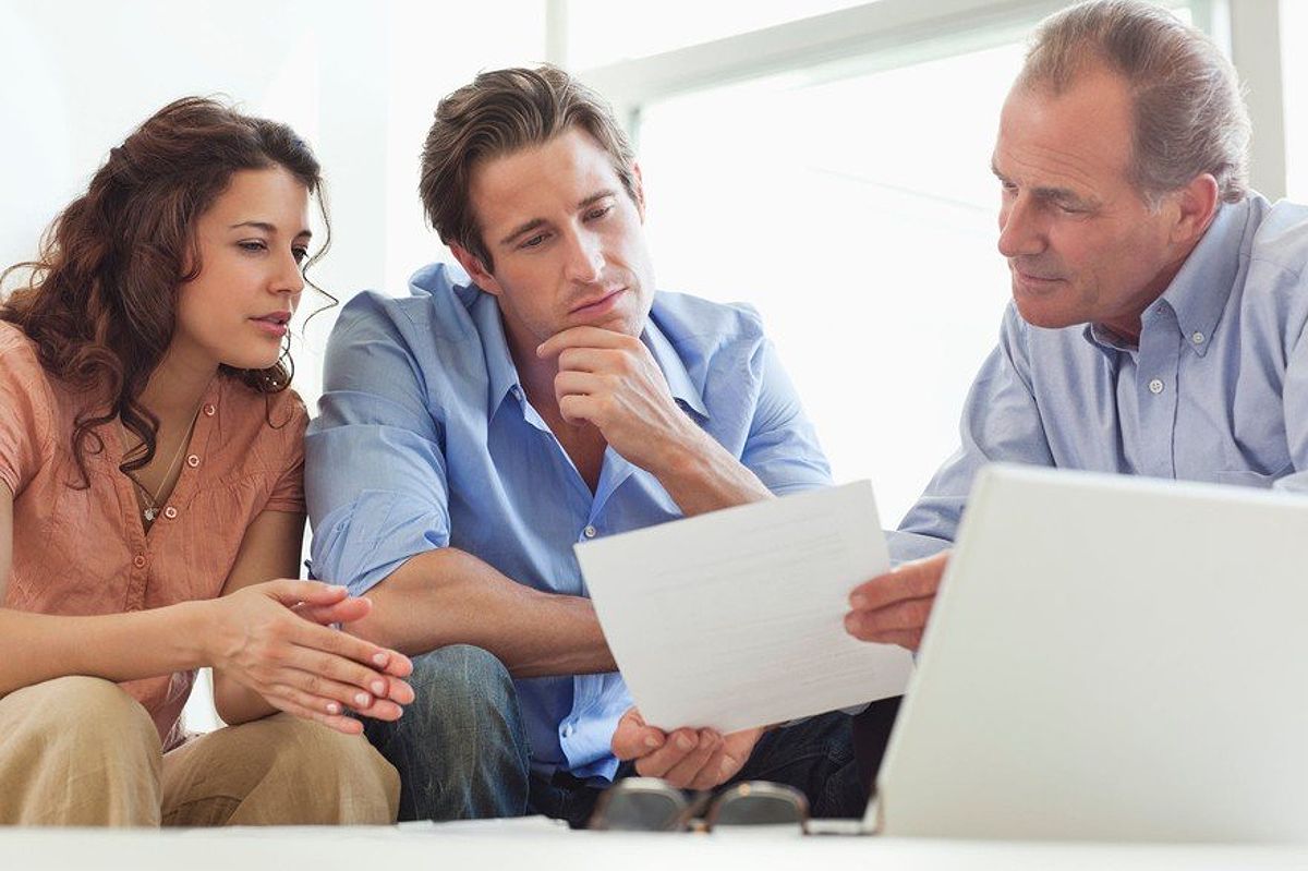 An older man showing a document to a man and a woman